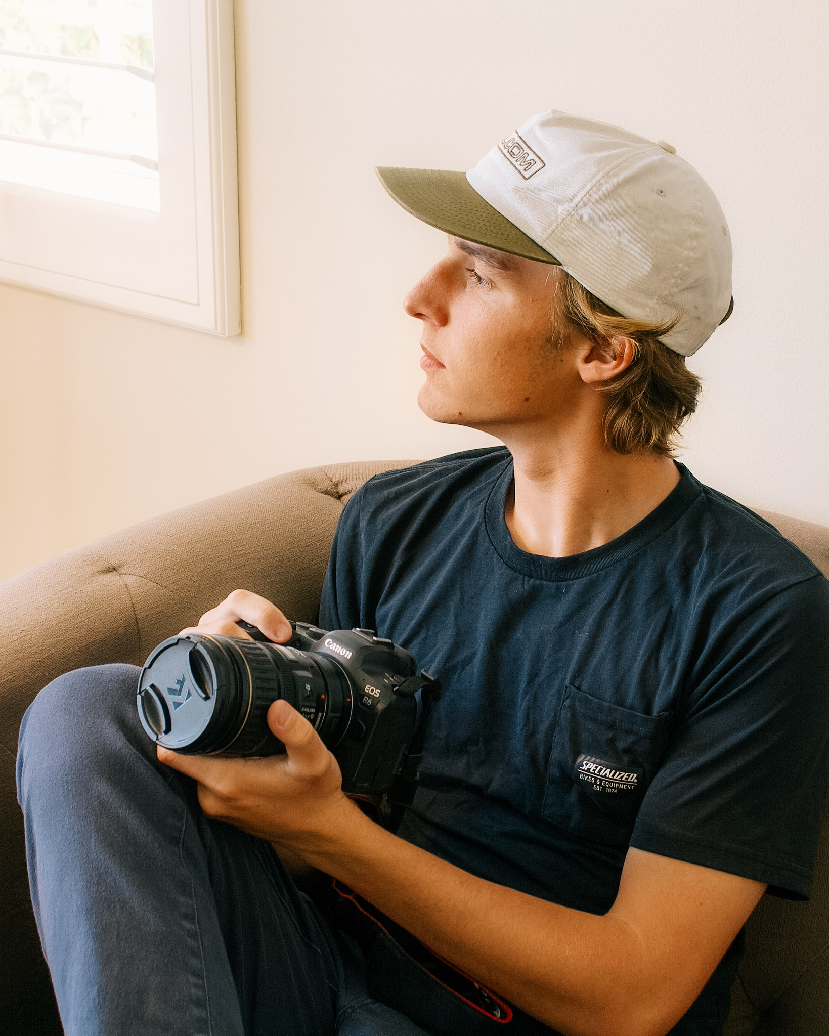 A warm self portrait of Judah Inman, sitting on a couch with his camera in hand